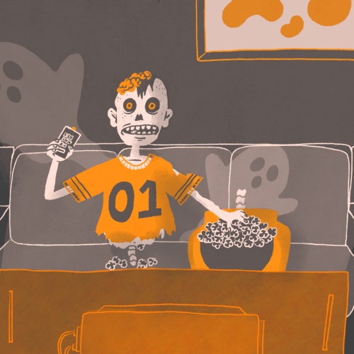 Halloween zombie sitting on a couch eating popcorn and watching TV