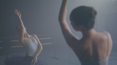 A ballet dancer practicing in front of a mirror.