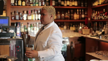 A bartender preparing a pink cocktail