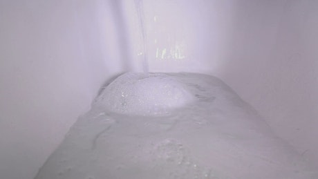A bathtub filling with water and bubbles.