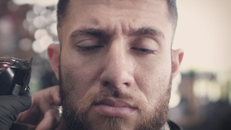 A bearded man getting a haircut
