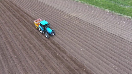A blue tractor working on the fields