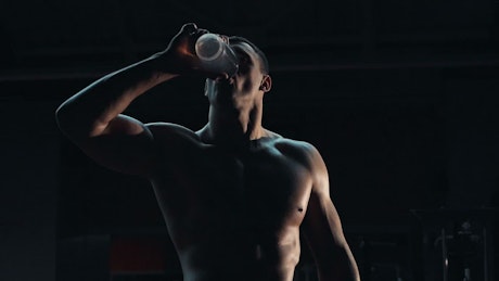 A bodybuilder is drinking water.