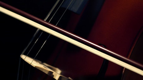 A bow being slowly dragged across the strings of a cello.