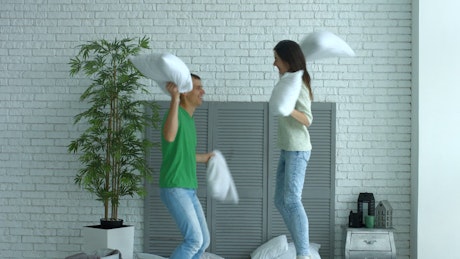 A boy and a girl fighting with pillows