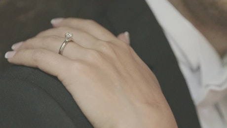 A bride's hand on the groom's shoulder at their wedding