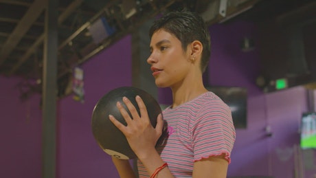 A brunette woman play bowling.