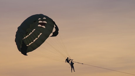 A couple enjoys parasailing in the sunset.