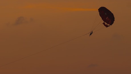 A couple enjoys parasailing in the sunset wind