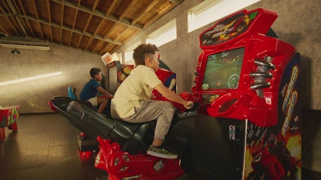 A couple of little kids enjoying the arcade racing bikes.