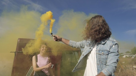 A couple playing with a yellow smoke bomb