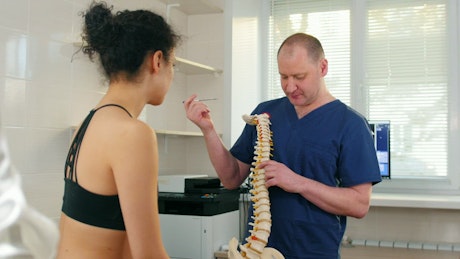 A doctor shows a spine to an athlete