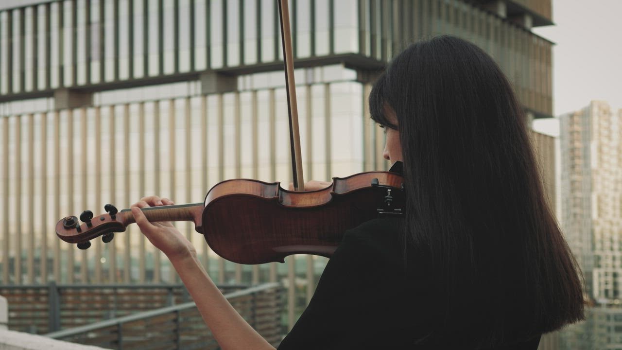 A female violinist playing music on a rooftop - Free Stock Video