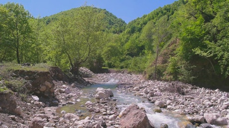 A flowing stream between mountains and rocks.