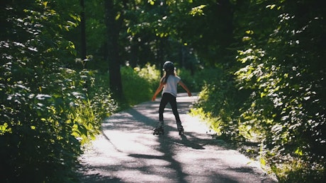 A girl skating on a park road.