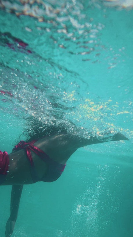 A girl swimming in a pool seen from underwater.