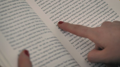 A girl's hand with a book following the reading with her finger on the page