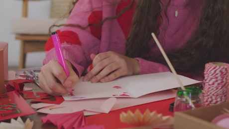 A girl's hands embellishing a Valentine's Day card.