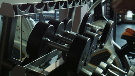 A guy taking the dumbbells in the gym.