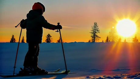 黄昏时，一个穿着滑雪装备的孩子在雪地上行走