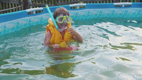 A little boy swimming in an inflatable pool.