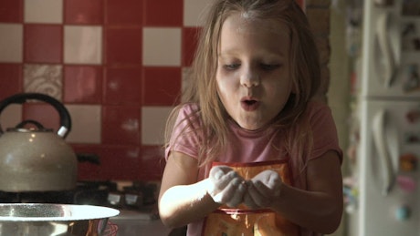 A little girl blowing flour