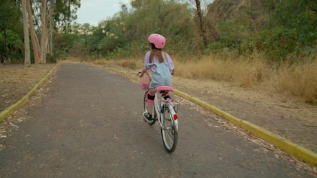 A little girl cruises through the forest path on her bike.