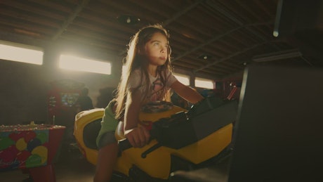 A little girl thrilled with an arcade motorbike.