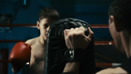 A little kid training boxing on the ring