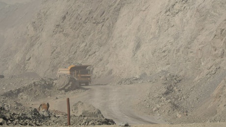 A loaded truck driving through a dusty mining quarry.