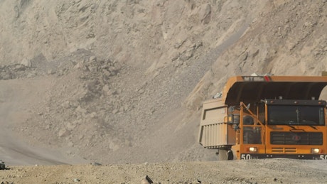 A loaded truck driving through a mining quarry site.