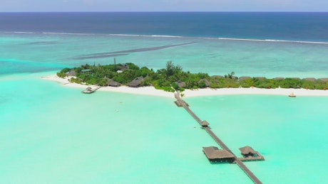 A luxury tourist island with a pier and bungalows