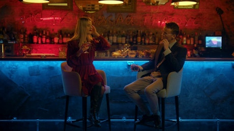 A man and a woman chatting in a bar.
