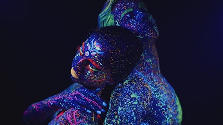 A man and a woman leaning against each other covered in paint.