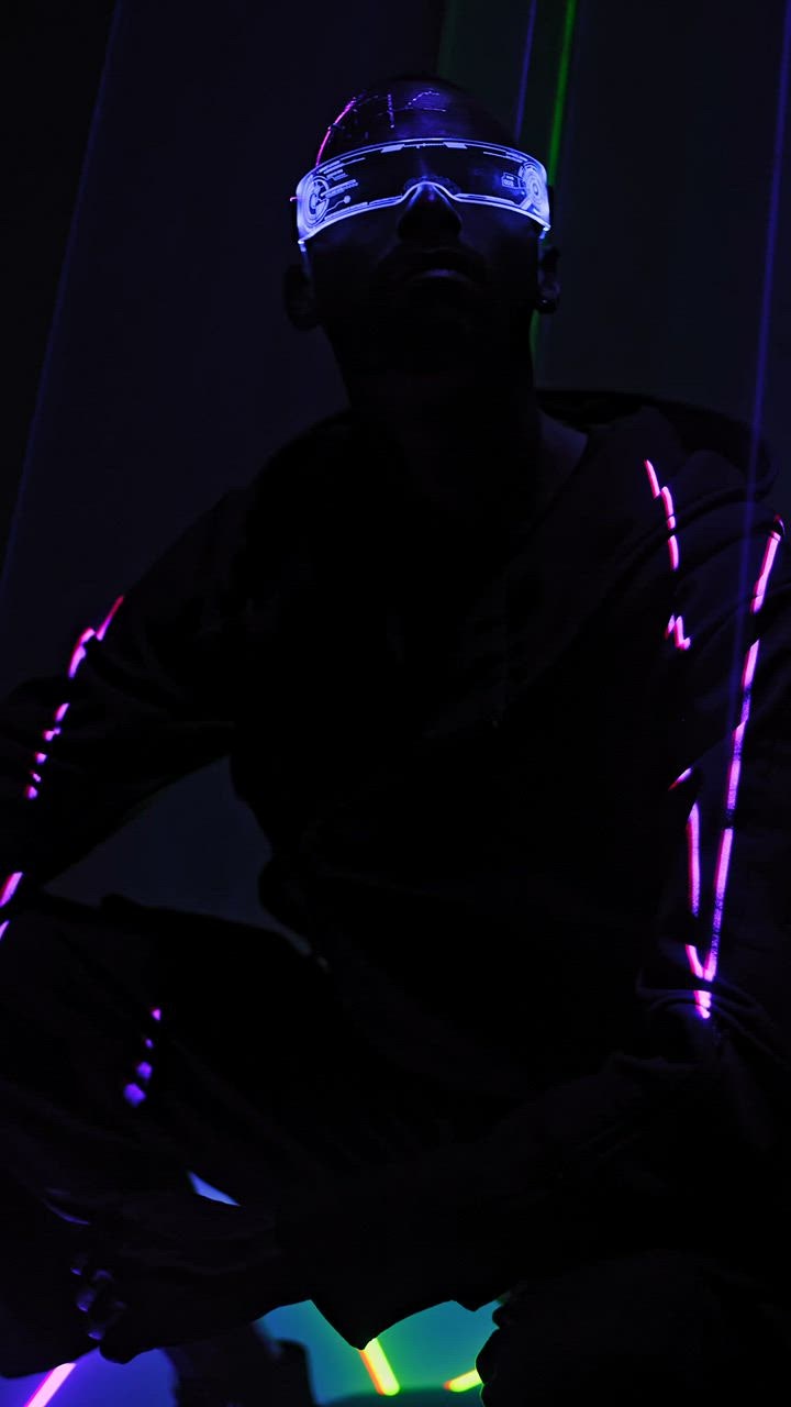 ⁣A man sitting beneath laser  live draw super wuhan lights in cyberpunk glasses