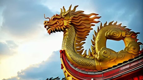 在中国的新年庆典上，一尊巨大的金龙雕像在蓝天下燃放烟花