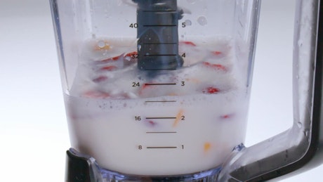 A mix of fresh colorful fruits mix on a blender.