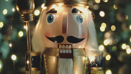 A Nutcracker Puppet with a Christmas tree in the background.