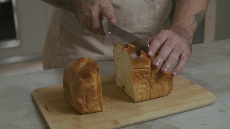 A pastry chef slicing a loaf into pieces.
