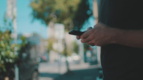 A person in the street messaging on a smartphone
