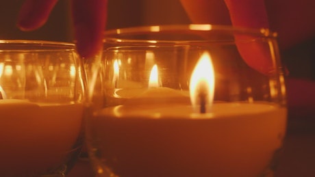 A person's hand accommodating small candles.