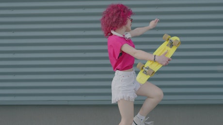 A pink curly haired girl enjoying her walk on the street.