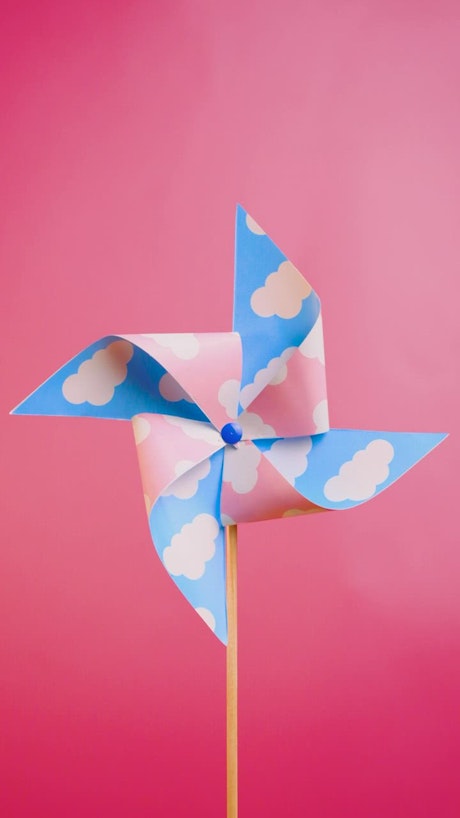 A pinwheel spinning on a pink background.