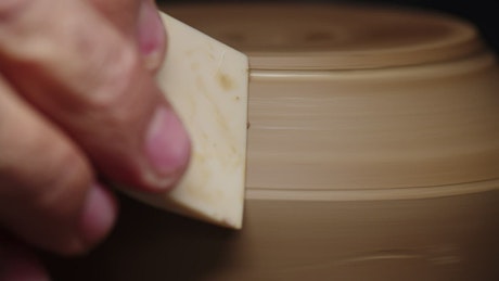 A potter slowly carves a vase of clay.