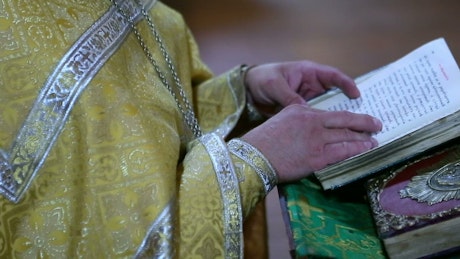 A priest stands at an alter reading a prayer.