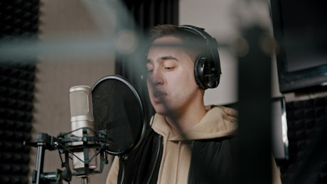 A rapper with headphones recording in the Studio