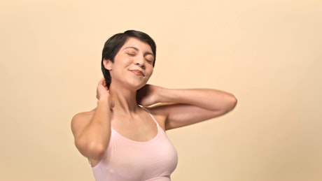 A smiling young woman with black short hair and a pink top poses over a beige backdrop.