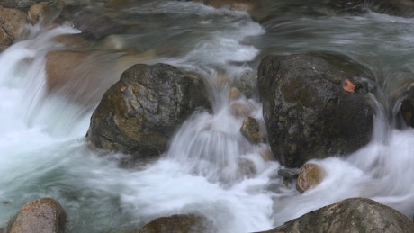 A stream flows between river rocks.