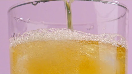 一股黄色的啤酒流充满水晶杯，产生啤酒泡沫