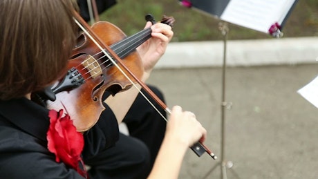A violinist performing outside with an orchestra.